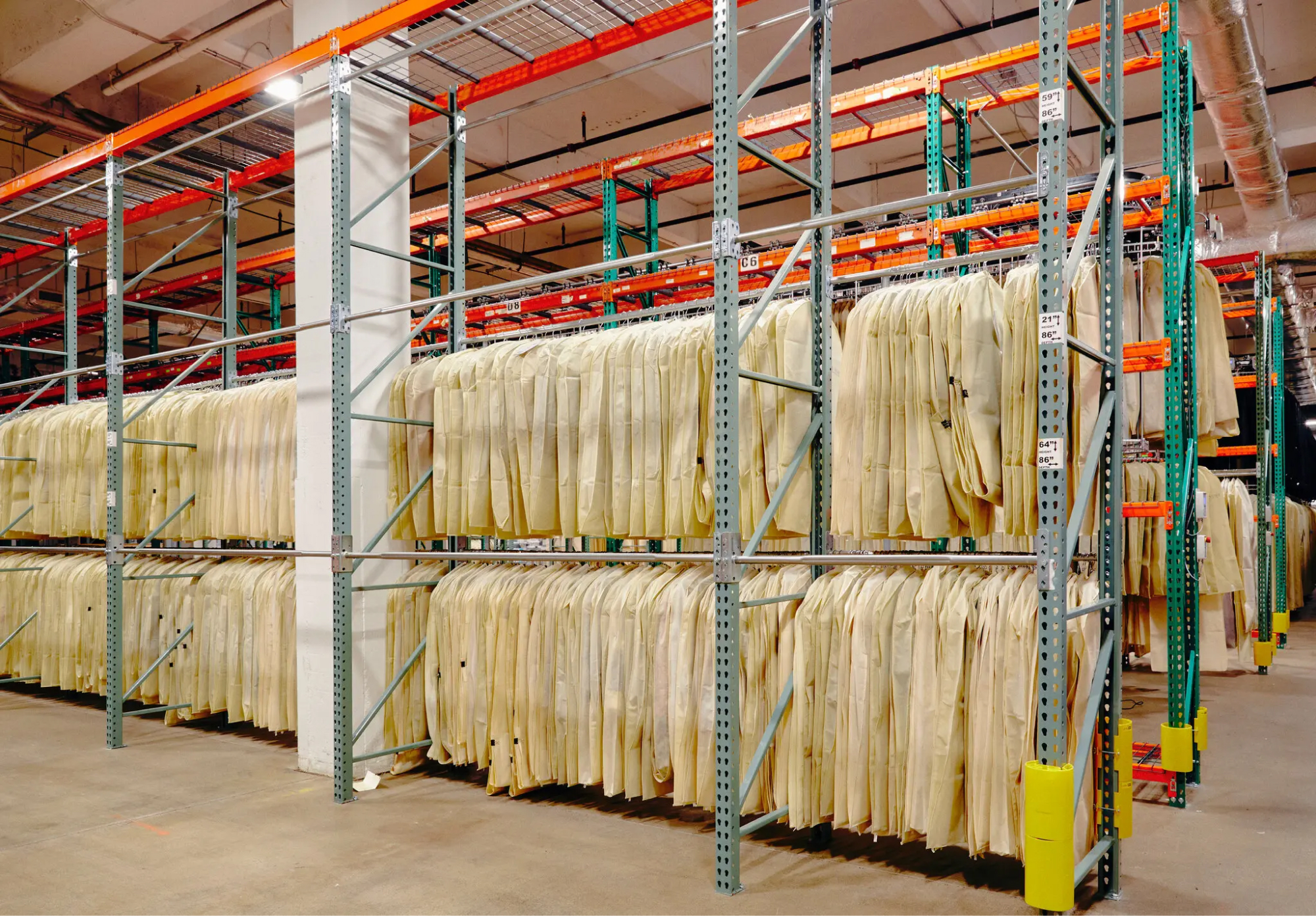 Expansive warehouse space filled with multi-level racks of yellow-colored garment bags.
