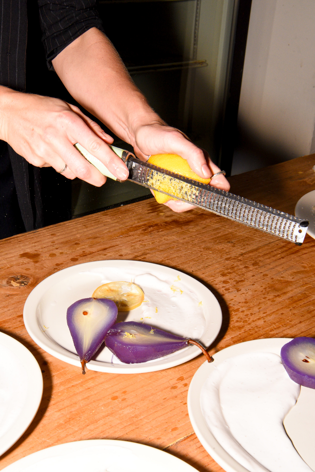 Close up image of person zesting lemon onto poached pears at a Rococo event.